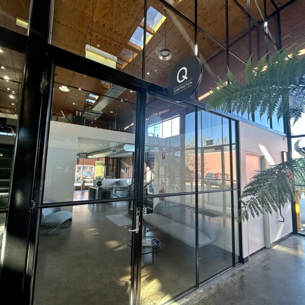 Internal view of a large office space, windows and doors cover the front of the tenancy, through the windows is a black staircase and over top is a timber roof, Hamilton property Group