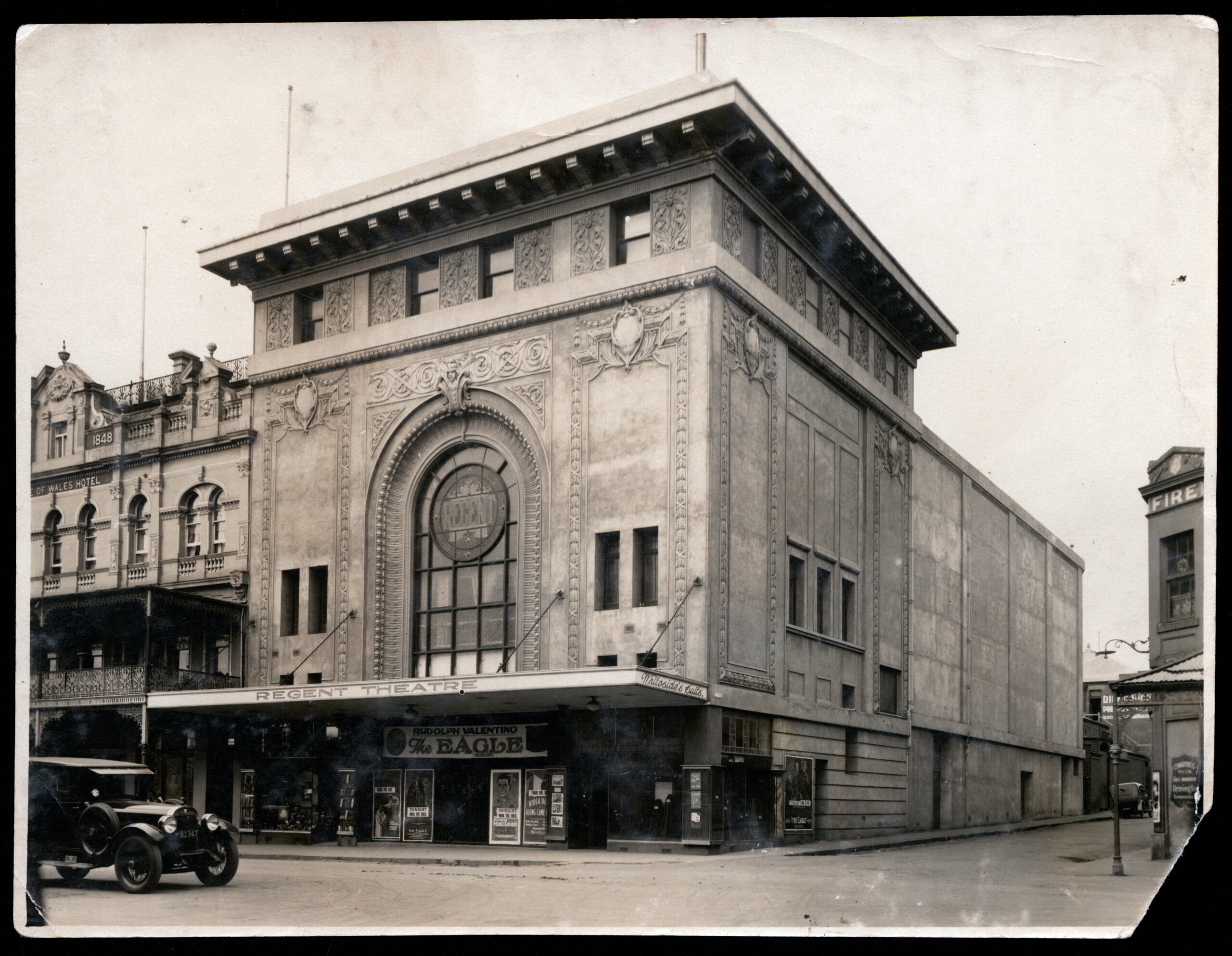 1920's vintage photo of original regent theatre, street view with old car driving in front, large awning on the front of the building, windows running front top to bottom, now owned by Hamilton Group Geelong