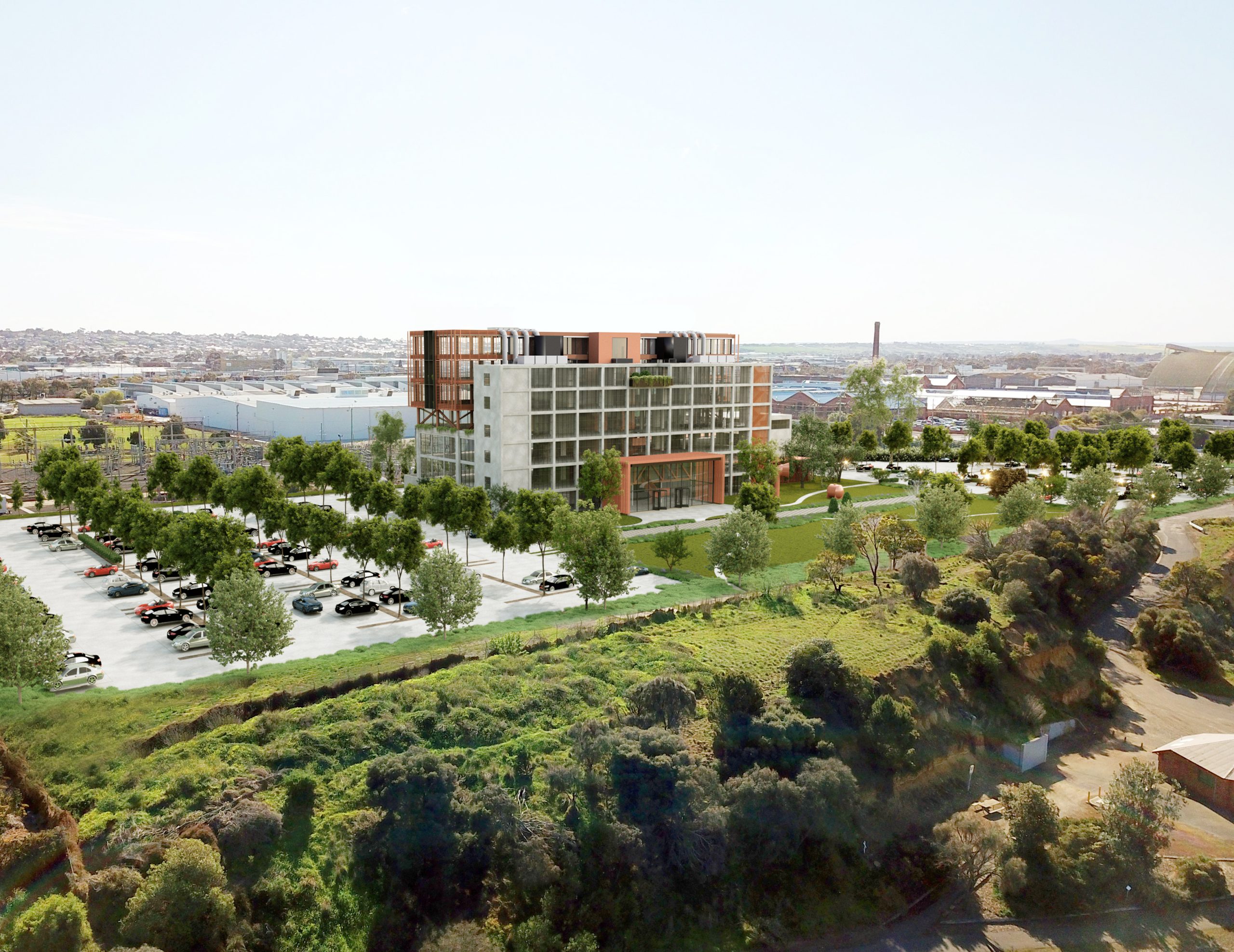 A rendered architectural visualization of a modern multi-story building in North Geelong, surrounded by landscaped green spaces and a large parking lot with trees. The building features glass facades, concrete elements, and a rooftop structure with industrial design elements. In the background, industrial warehouses, historic brick buildings, and a distant smokestack are visible. A natural green embankment with trees and shrubs is in the foreground.