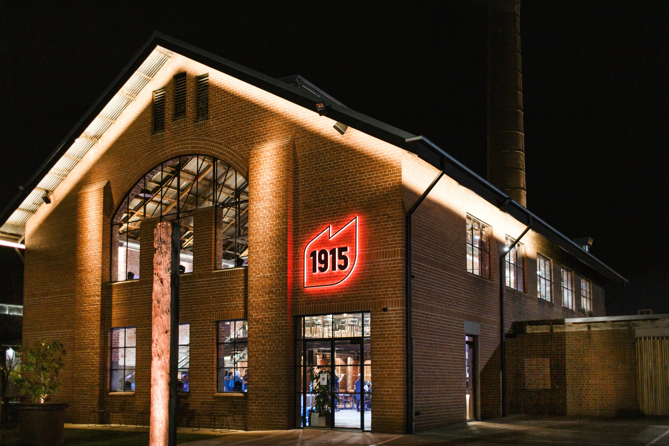 1915 restaurant at night lit up by warm lights with a large red sign on the front