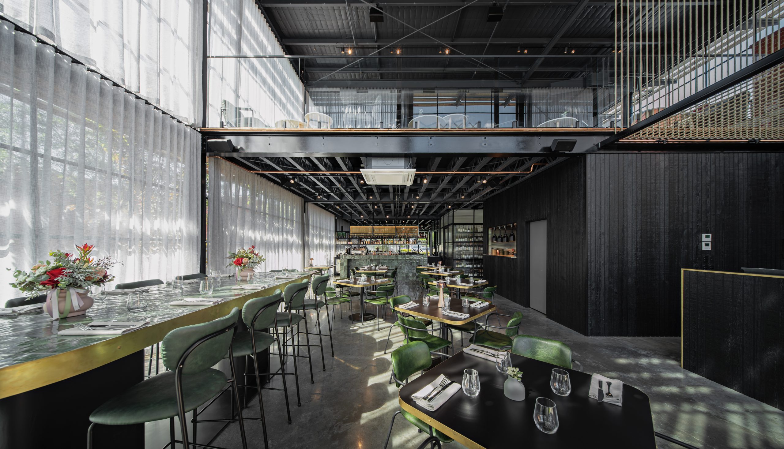 Internal view of the famous Woolstore restaurant in Geelong, it features rustic green chairs surrounding low black tables