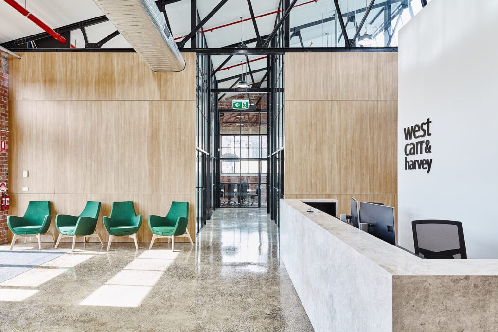 Red brick walls surround stylish office fit out, modern green chairs in front of tall timber dividing walls, t-bar windows line lengthy hallway, curated by Hamilton Group Geelong