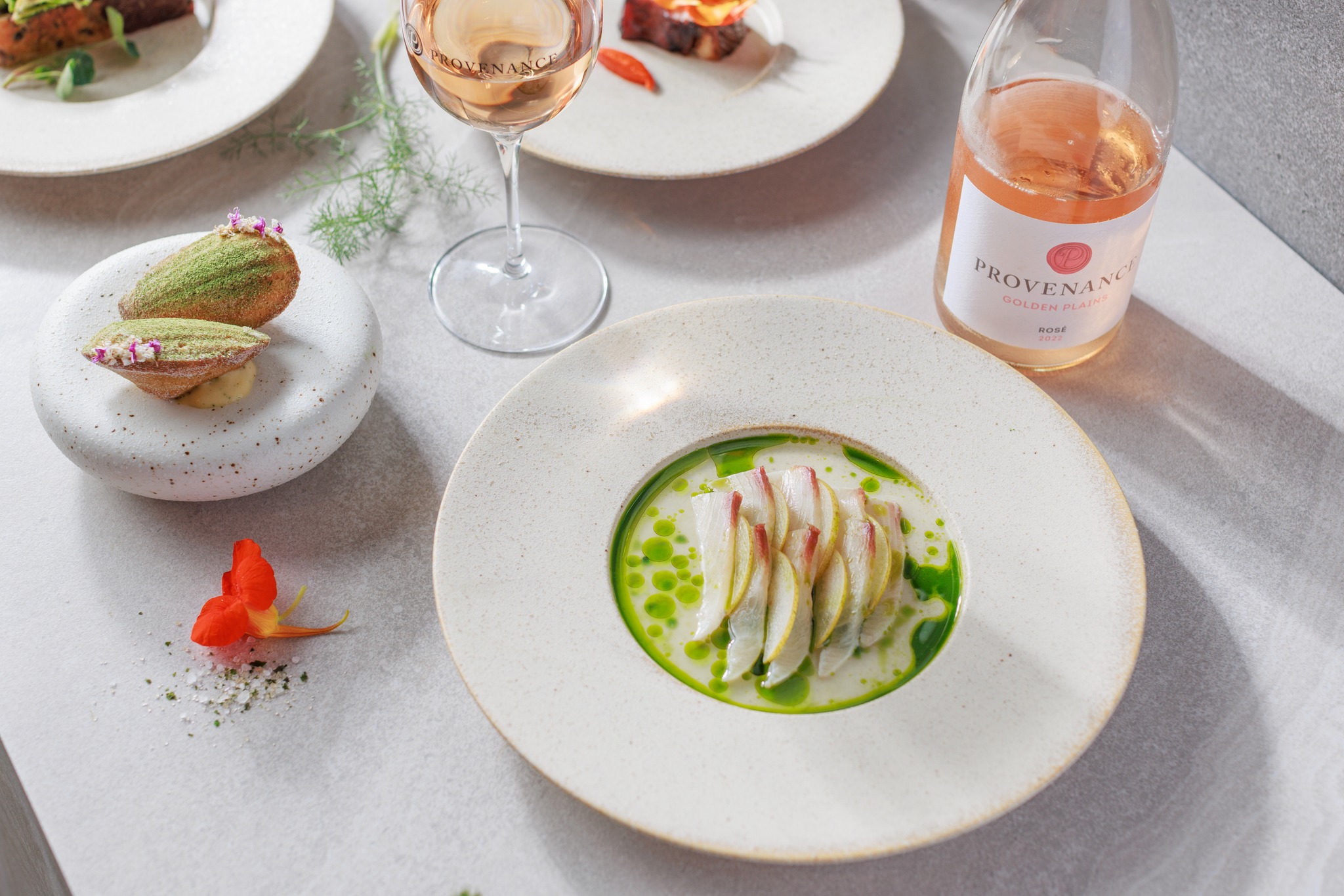 Delicious king fish meal produced by the Provenance restaurant within the Fyansford Paper Mills precinct, a bottle of rose wine with a cup half full next to it, a beautiful orange flower to the left of the meal and behind that in a desert, Hamilton Group Geelong