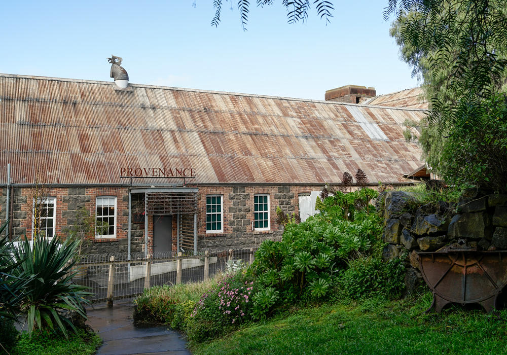 A restaurant located within the Fyansford Paper Mills precinct, Provenance wines is in an old paper making shed, it has a beautiful blue stone and red brick facade with an old corrugated roof, it surrounded by a lush green garden in front with an old steel drum for decoration, this property is now owned by Geelong's Hamilton Property Group